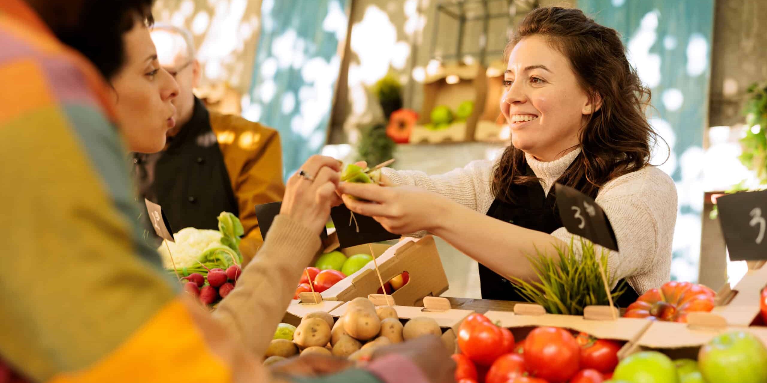 Woman handing out produce at farmers market